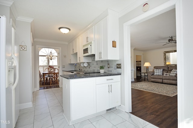 kitchen with white appliances, white cabinets, crown molding, and backsplash