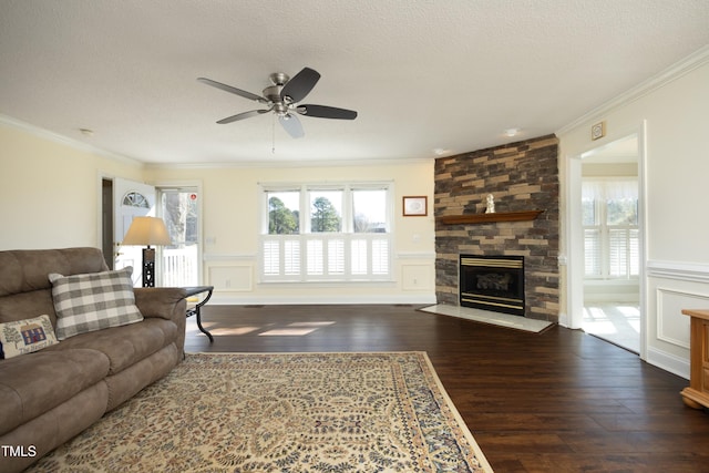 living area featuring a fireplace, crown molding, wood finished floors, and a textured ceiling