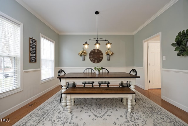 dining space featuring light wood-type flooring and ornamental molding