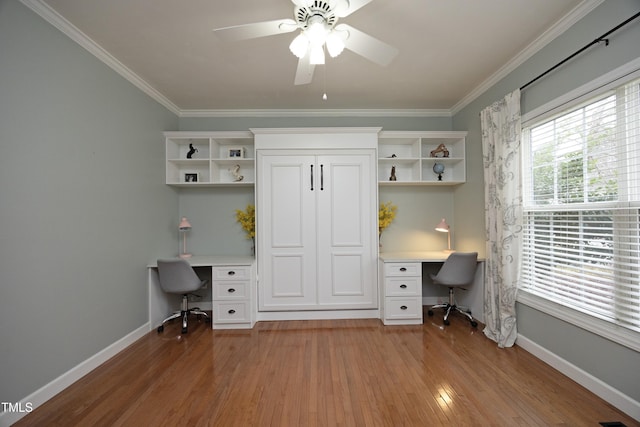 unfurnished office with crown molding, hardwood / wood-style flooring, built in desk, and ceiling fan