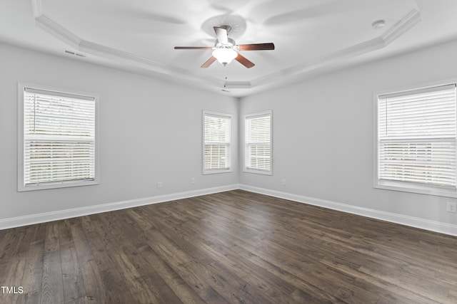 unfurnished room featuring ceiling fan, dark hardwood / wood-style flooring, a raised ceiling, and a wealth of natural light