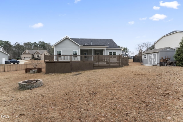 back of house with a storage shed, a wooden deck, and an outdoor fire pit