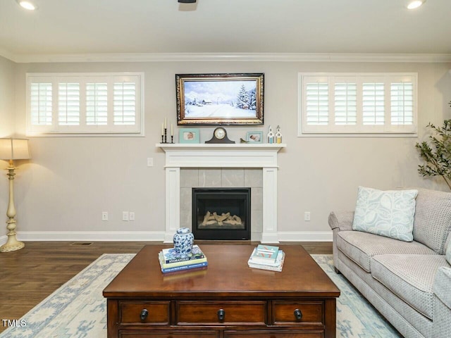 living room featuring dark hardwood / wood-style floors, ornamental molding, and a tile fireplace