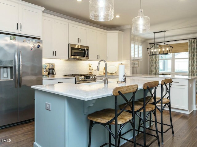 kitchen featuring pendant lighting, white cabinetry, decorative backsplash, a kitchen island with sink, and stainless steel appliances