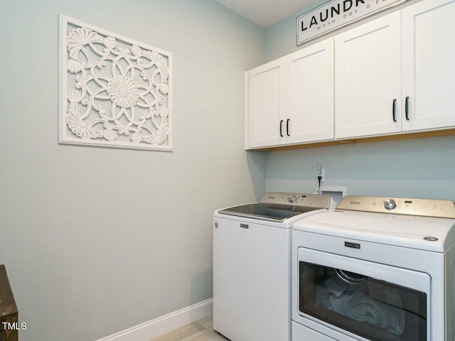 clothes washing area with cabinets and washer and clothes dryer