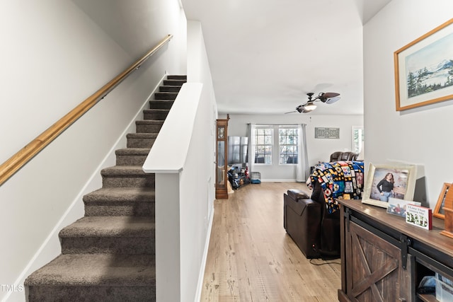 stairway with wood-type flooring and ceiling fan