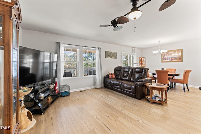 living room featuring ceiling fan with notable chandelier and light hardwood / wood-style flooring