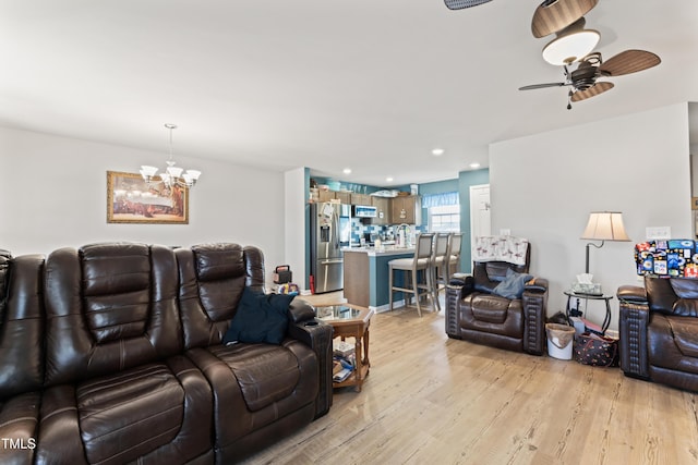 living room with ceiling fan with notable chandelier and light hardwood / wood-style flooring