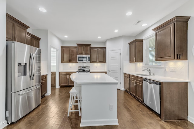 kitchen featuring sink, appliances with stainless steel finishes, dark hardwood / wood-style flooring, a kitchen island, and a wealth of natural light