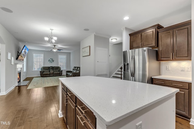 kitchen with stainless steel refrigerator with ice dispenser, tasteful backsplash, a center island, dark hardwood / wood-style floors, and ceiling fan