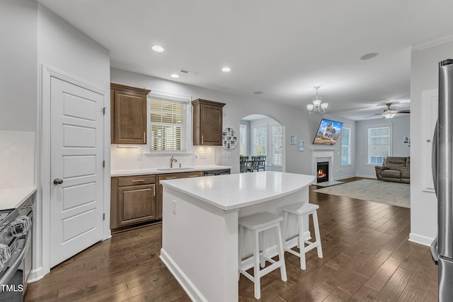 kitchen with sink, a breakfast bar area, a center island, dark hardwood / wood-style floors, and stainless steel appliances