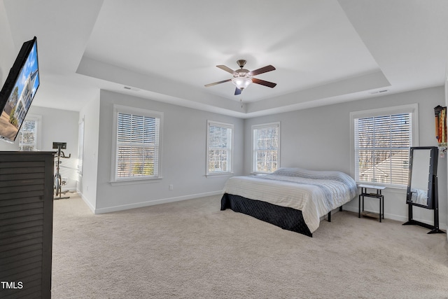 bedroom with light colored carpet, ceiling fan, and a tray ceiling