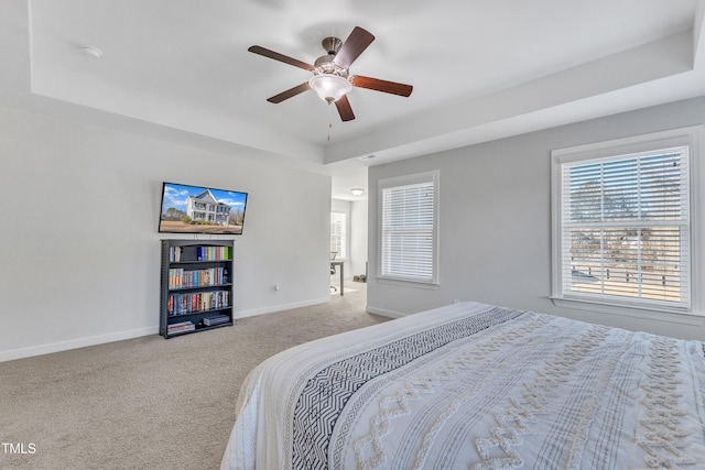 carpeted bedroom featuring a raised ceiling and ceiling fan