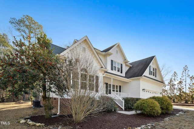 view of front of house with a garage, central air condition unit, and a porch