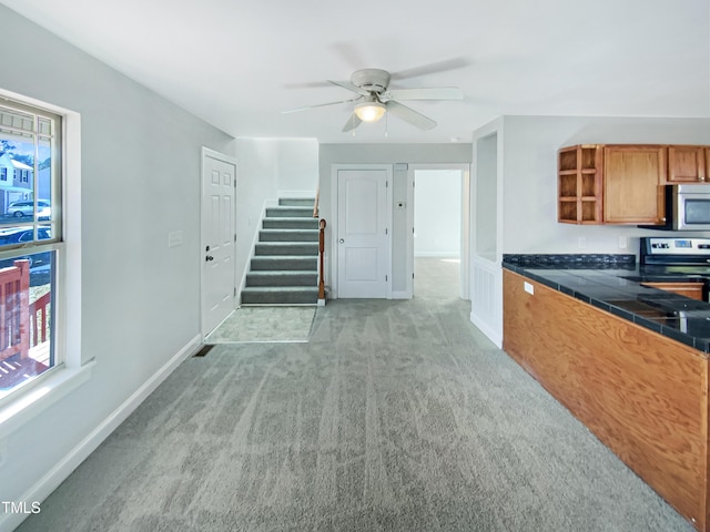 kitchen with appliances with stainless steel finishes, light colored carpet, and ceiling fan