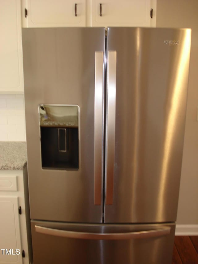 interior details with stainless steel refrigerator with ice dispenser, dark wood-type flooring, white cabinetry, tasteful backsplash, and light stone countertops