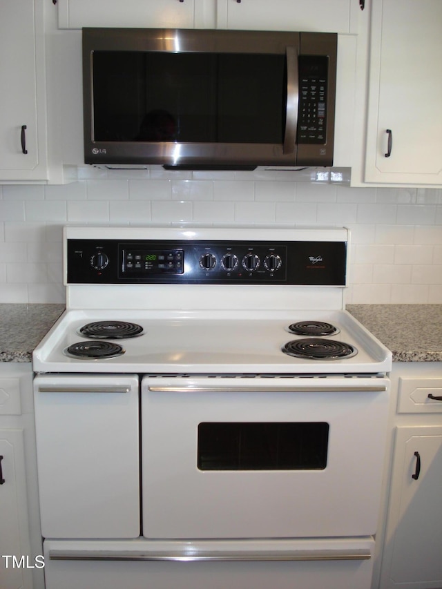 kitchen with double oven range, light stone countertops, and white cabinets