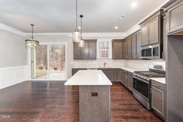 kitchen featuring hanging light fixtures, crown molding, stainless steel appliances, and a center island