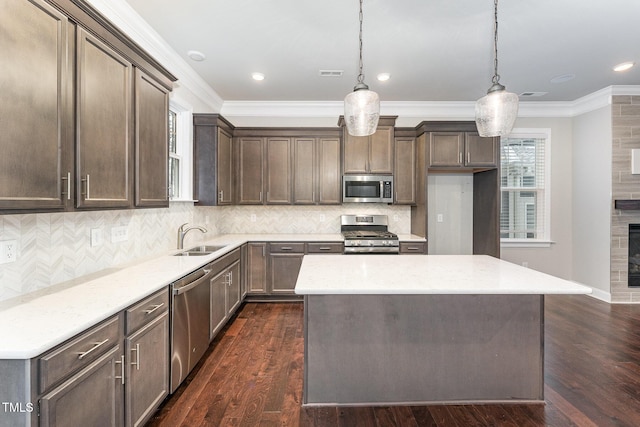 kitchen with appliances with stainless steel finishes, dark hardwood / wood-style floors, decorative light fixtures, sink, and light stone counters