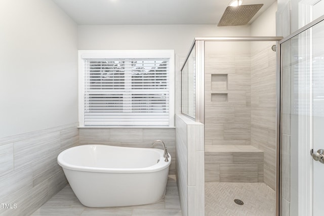 bathroom with shower with separate bathtub and tile walls