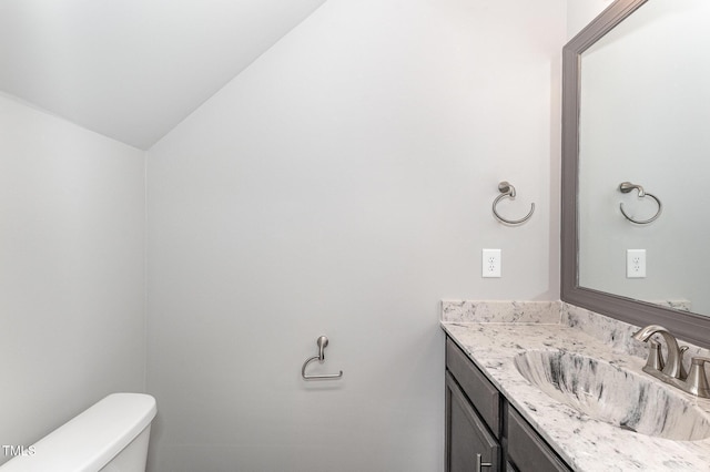 bathroom featuring lofted ceiling, vanity, and toilet