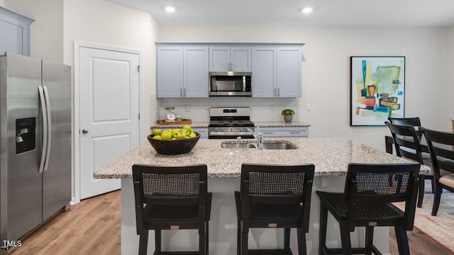 kitchen featuring sink, stainless steel appliances, an island with sink, and a kitchen bar