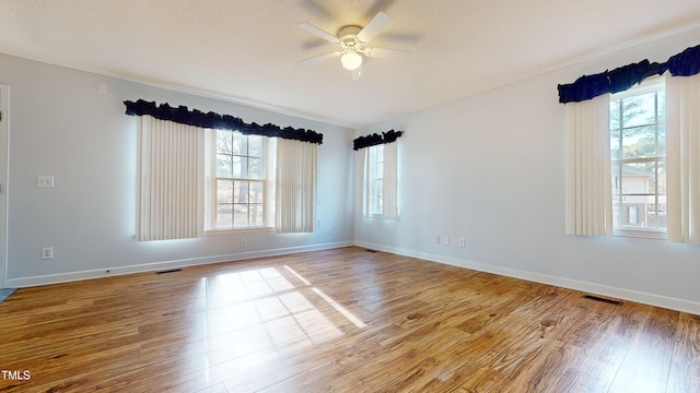 empty room with ceiling fan, a textured ceiling, and light hardwood / wood-style floors