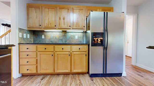 kitchen with light hardwood / wood-style flooring, stainless steel fridge with ice dispenser, decorative backsplash, and dark stone countertops