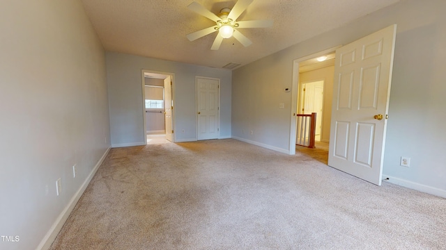 empty room featuring ceiling fan, light carpet, and a textured ceiling