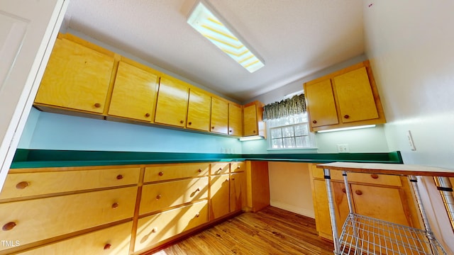 kitchen featuring lofted ceiling, a textured ceiling, and light wood-type flooring