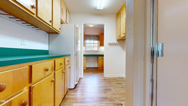 kitchen with white refrigerator, light hardwood / wood-style flooring, and a textured ceiling