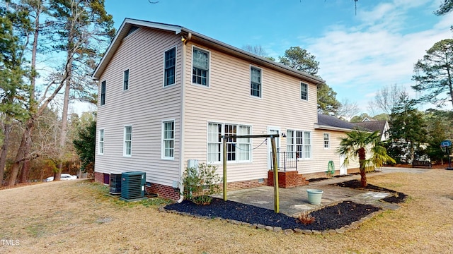 rear view of house with cooling unit, a yard, and a patio