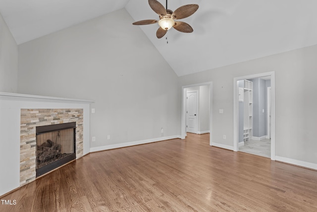 unfurnished living room featuring ceiling fan, a stone fireplace, high vaulted ceiling, and light hardwood / wood-style floors