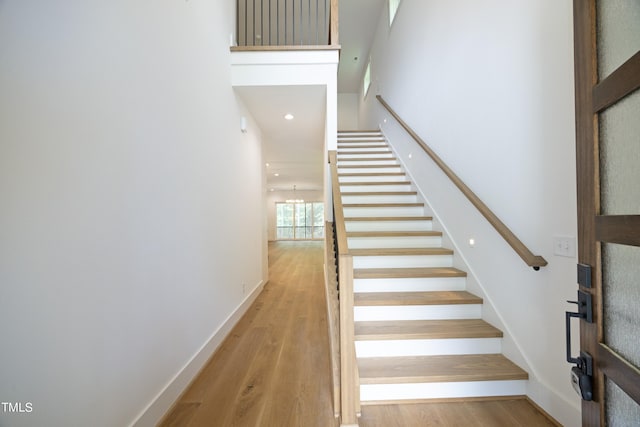 staircase featuring wood-type flooring and a chandelier