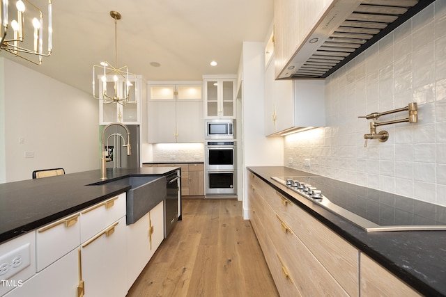 kitchen with hanging light fixtures, backsplash, stainless steel appliances, white cabinets, and wall chimney exhaust hood