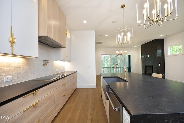 kitchen with decorative backsplash, hanging light fixtures, a notable chandelier, light hardwood / wood-style floors, and black electric cooktop