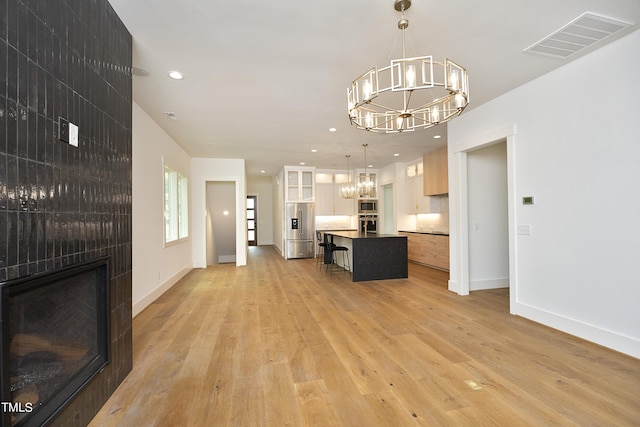 kitchen with a breakfast bar, an inviting chandelier, a center island, pendant lighting, and stainless steel appliances