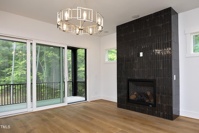 unfurnished living room with hardwood / wood-style floors, a notable chandelier, and a fireplace