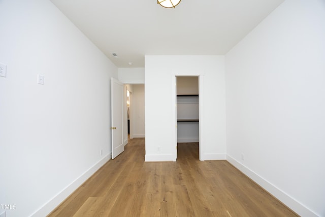 unfurnished bedroom featuring a spacious closet, light hardwood / wood-style flooring, and a closet