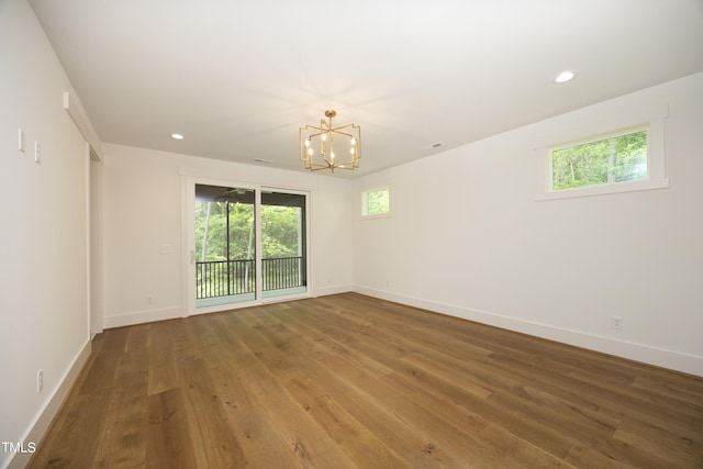 empty room featuring an inviting chandelier and hardwood / wood-style floors