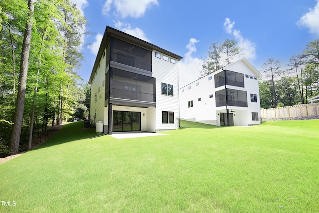 rear view of property with a sunroom, a patio, and a lawn