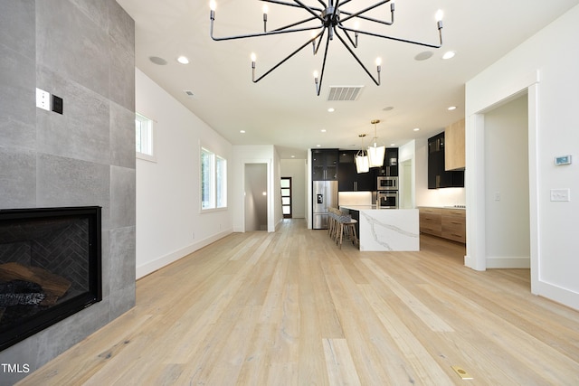 unfurnished living room featuring a tiled fireplace and light wood-type flooring