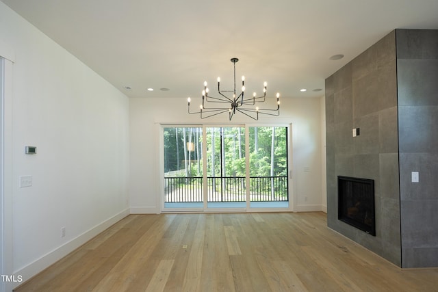 unfurnished living room with a chandelier, a tile fireplace, and light hardwood / wood-style flooring