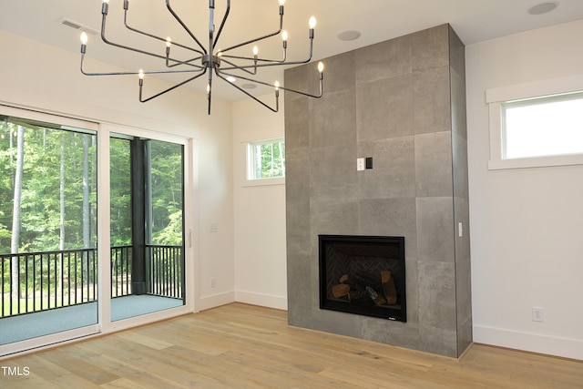 unfurnished living room featuring a notable chandelier, a fireplace, and light wood-type flooring