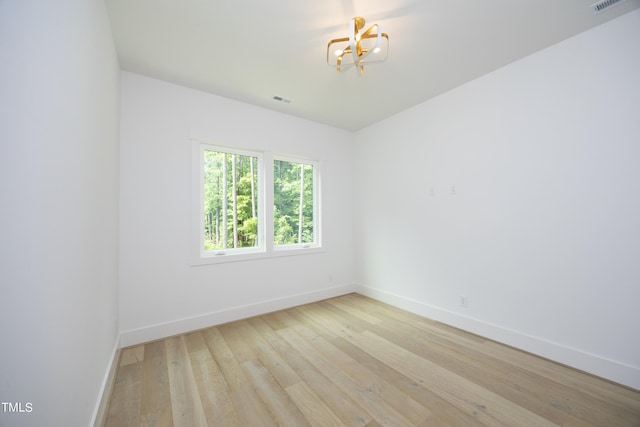 spare room with an inviting chandelier and light hardwood / wood-style flooring