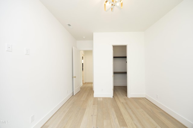 unfurnished bedroom with a walk in closet, light hardwood / wood-style floors, and a closet