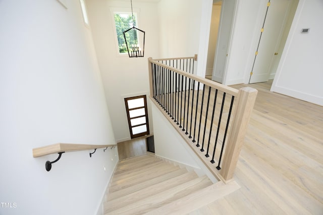 stairs featuring wood-type flooring and a chandelier