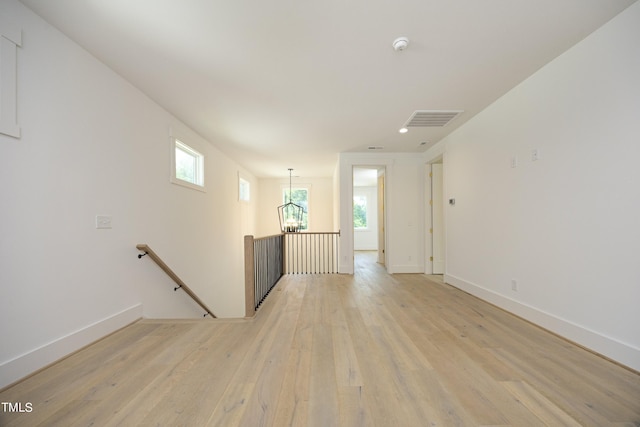 empty room with a notable chandelier and light hardwood / wood-style flooring