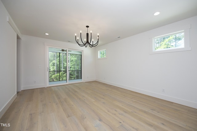 unfurnished room featuring a chandelier and light hardwood / wood-style flooring