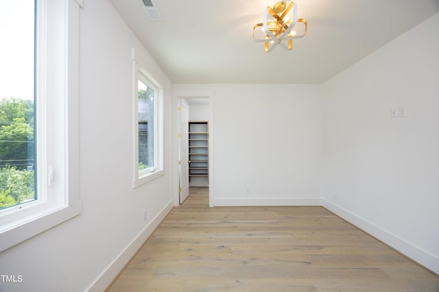 spare room featuring light hardwood / wood-style flooring and a notable chandelier